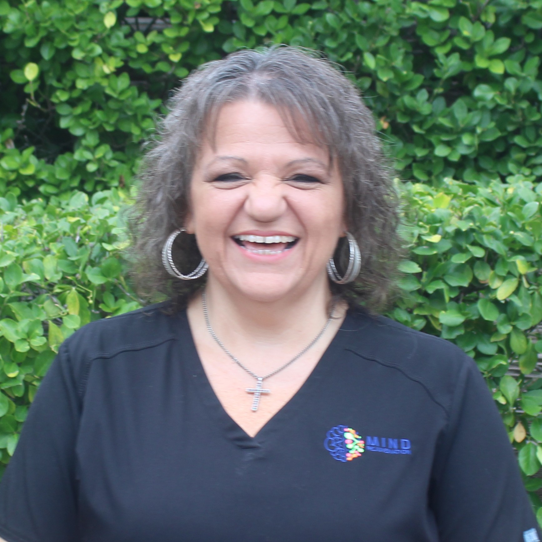 Peggy Shearl, Office Manager, Billing Specialist, and Prior Authorization Coordinator at Mind Rejuvenation, smiling in branded attire outdoors. Featured on the Meet Our Team page to reflect dedication, warmth, and behind-the-scenes expertise in patient care.